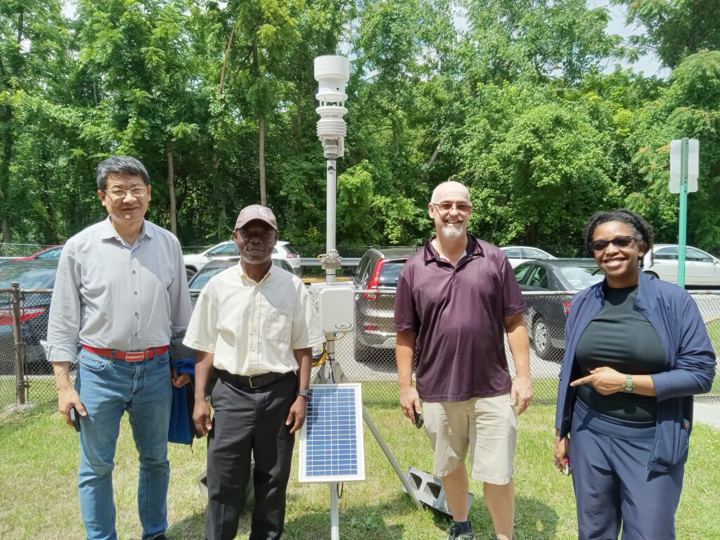 Atmospheric dynamics team standing in front of a weather monitor